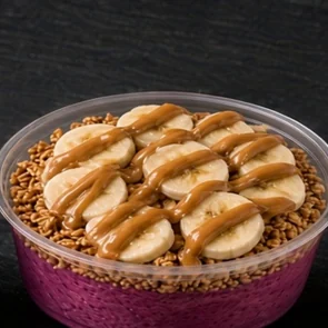 Dragon Power super bowl: pink dragon fruit base topped with banana slices and a peanut butter drizzle