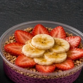 Pink Dragon bowl: dragon fruit base with granola, a ring of strawberries, banana slices and honey