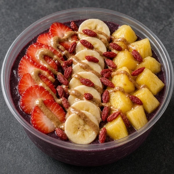 Berrylicious super bowl: açaí base topped with strawberries, banana slices, pineapple chunks, goji berries and an almond butter drizzle