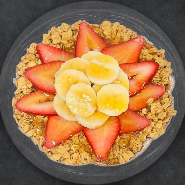 Coco Treat bowl: coconut base with granola, strawberries, banana slices and a honey drizzle